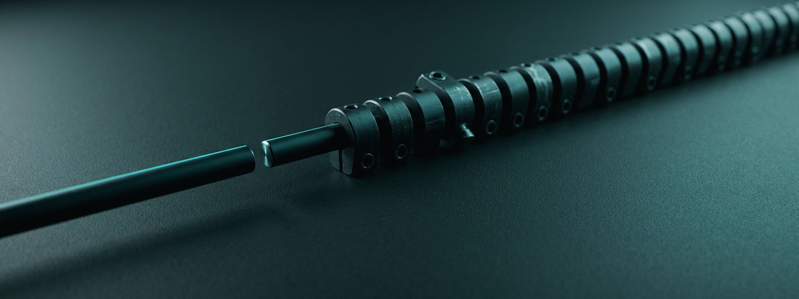 A dark machined shaft on a teal ground meeting a long stack of closely spaced collars, lit by a hard raking light so the ridges read as many small, evenly spaced increments.